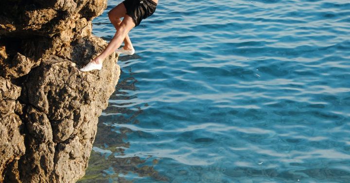 Water Activities - Man climbing on a rock by the sea