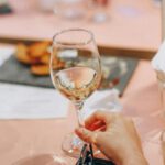 Dining Out - Person Holding Wine Glass Near Clear Shot Glasses