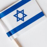 Cultural Identity - Top view collection of small paper flags of Israel on toothpicks placed in line on white surface