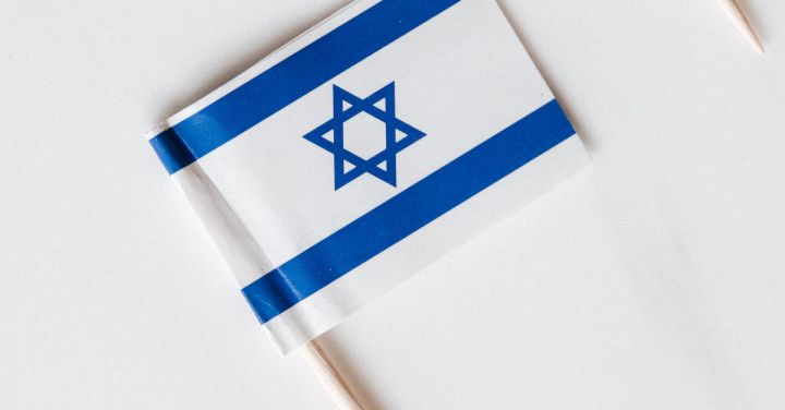 Cultural Identity - Top view collection of small paper flags of Israel on toothpicks placed in line on white surface