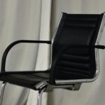 Accommodations - Black chair with leather seat and metal elements placed in light room against long curtain