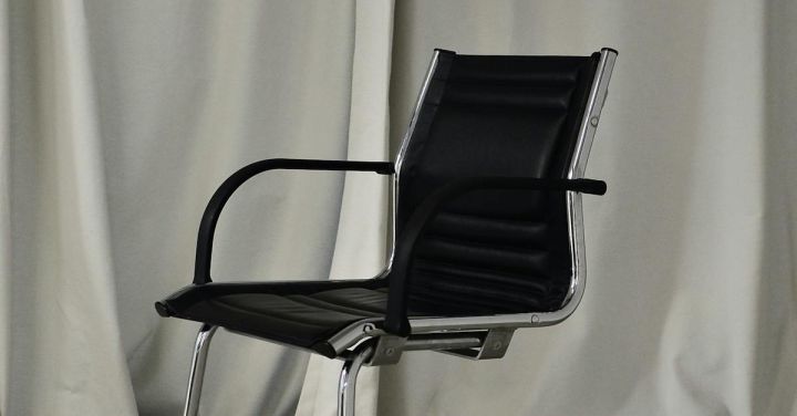 Accommodations - Black chair with leather seat and metal elements placed in light room against long curtain